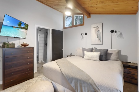 Sink into plush linens under soaring wood-beamed ceilings. Your private retreat features modern lighting, a smart TV, and an ensuite bathroom with clean tile finishes.