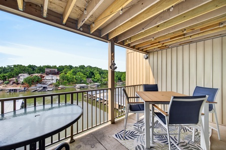 Relax on your private balcony with serene lake views, comfortable dining seating, and a shaded pergola overhead—perfect for morning coffee or evening unwind.