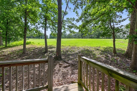 Mature trees frame rolling green fairways just beyond your private deck—a peaceful backdrop for morning coffee and evening relaxation.