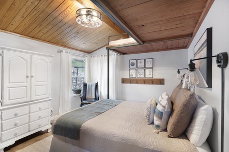 Drift off to sleep in your cozy bedroom with a plush bed, warm wood-beam ceiling, and natural light filtering through the window to greet you each morning.
