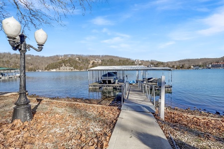 Private dock on tranquil lake waters surrounded by rolling hills and wooded shoreline.