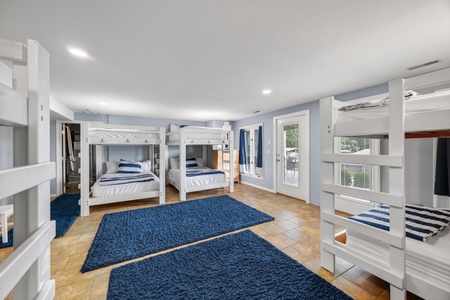 Step into your spacious bunkroom, where crisp nautical linens and soft blue rugs create a cozy harbor for restful sleep. Natural light pours through the patio door, inviting you to wake up and step outside.