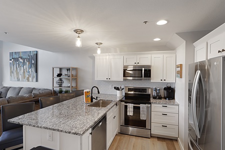 Your modern kitchen awaits with gleaming granite counters, stainless appliances, and bright white cabinets—perfect for morning coffee or cooking together.