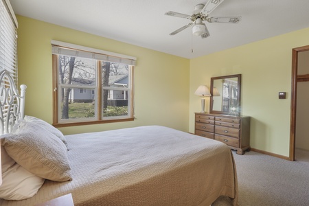 Unwind in this bright, airy bedroom with soft yellow walls and comfortable furnishings that create a peaceful retreat for restful nights.