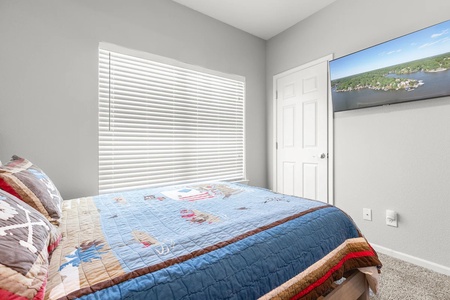 Drift into peaceful sleep in your cozy bedroom with soft natural light filtering through custom blinds and a large-screen TV for relaxing evenings.