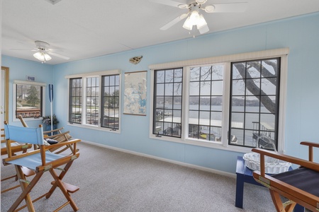 Relax in your bright sunroom with waterfront views through large windows, featuring comfortable seating and gentle ceiling fans for perfect lake breezes.