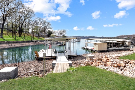 Lakefront marina with private boat docks and covered slips nestled along peaceful waters surrounded by rolling hills and spring greenery.