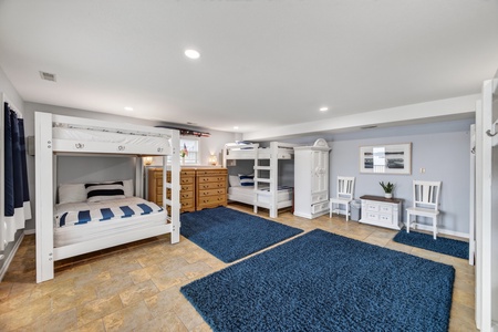 Your spacious bunk room awaits, with custom white bunk beds and plush navy rugs underfoot, designed to keep everyone together while giving everyone their own cozy spot to unwind after a day of adventure.