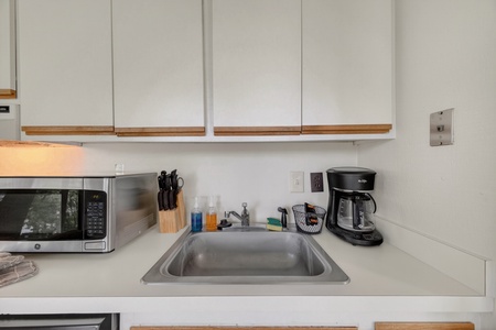 Your fully equipped kitchenette features stainless steel appliances, ample cabinet space, and a coffee maker ready for your morning brew—everything you need to whip up a quick meal or snack.