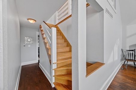 The warm wood staircase leads you up to your private retreat, with clean white railings and polished floors welcoming you home.