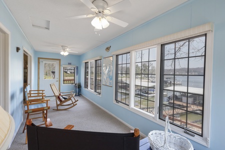 Unwind in your peaceful sunroom with comfortable seating and stunning lake views through panoramic windows.