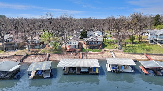Lakeside community aerial view showcasing waterfront properties with private boat docks along the shoreline during late winter.