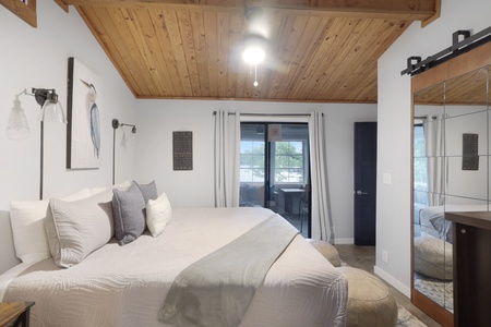 Drift into a peaceful night's sleep under soaring wood-paneled ceilings, with plush linens inviting you to unwind and your own private hot tub awaiting just beyond those doors.