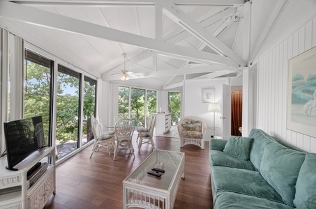 Sink into the plush teal sofa and feel the warmth of natural light streaming through tall windows as coastal breezes fill this airy, open retreat.