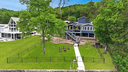 Lakefront vacation home nestled in lush greenery, featuring elevated deck living and a private dock leading to waterfront adventures.