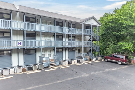 A three-story vacation rental property featuring private balconies and convenient ground-level parking surrounded by lush greenery.