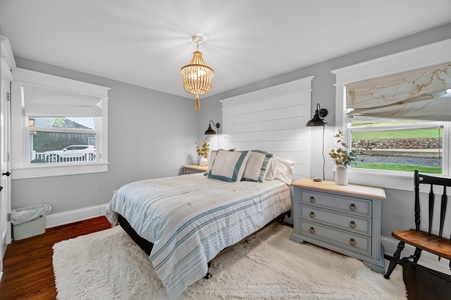 Drift off in your charming bedroom, where soft grey walls meet coastal-inspired linens and a statement chandelier casts a warm glow overhead.