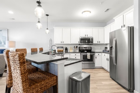 Your fully equipped kitchen features granite countertops, stainless steel appliances, and a breakfast bar perfect for morning coffee or evening meals.