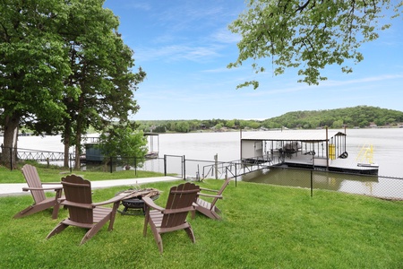 A serene lakefront setting with private dock, Adirondack chairs, and fire pit where you can unwind waterside under the shade of mature trees.