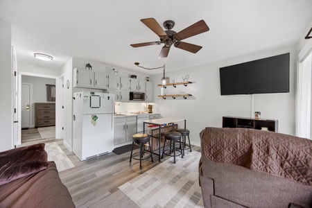 Step into your cozy, open-plan retreat where a fully equipped kitchen, comfortable seating, and modern entertainment await. The ceiling fan keeps you cool while you relax in this bright, welcoming space.