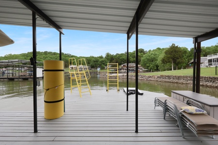 Your private lakefront dock awaits with direct water access, a covered lounging area, swim ladder, and scenic views of wooded shores—perfect for relaxing, swimming, or launching your lake adventures.