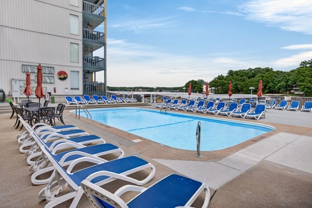 Sparkling outdoor pool with ample lounge seating, framed by waterfront views and lush green surroundings—your perfect spot to soak up the sun and unwind in style.
