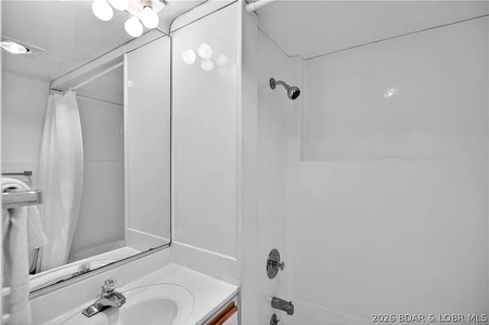 A clean, well-lit bathroom awaits with a spacious shower-tub combo, fresh towels, and a large mirror to start your mornings refreshed.