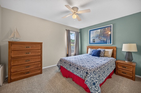 Sink into crisp linens under a gentle ceiling fan in your serene coastal bedroom, with warm wood tones and nautical touches creating a peaceful retreat after a day of exploring.