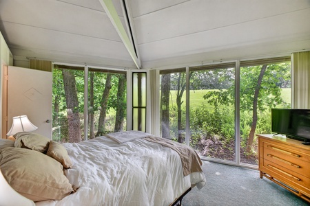 Wake to serene forest views from your bed, with floor-to-ceiling windows bringing nature right into your peaceful retreat. Sunlight filters through the trees, creating a tranquil sanctuary for rest.