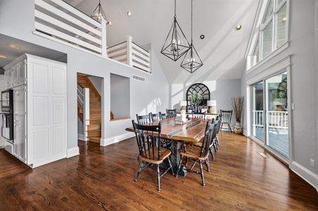 Gather around the stunning live-edge dining table beneath soaring cathedral ceilings and elegant pendant lighting. Natural light floods through expansive windows, creating a warm, inviting space perfect for memorable meals together.