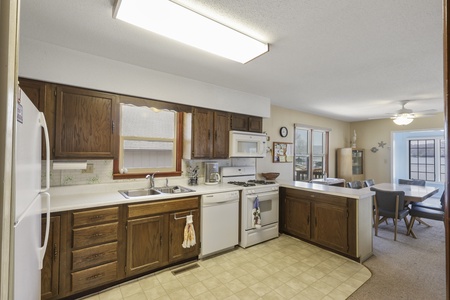 Your fully equipped kitchen awaits with everything needed to prepare meals, featuring rich wood cabinets and convenient breakfast bar seating.