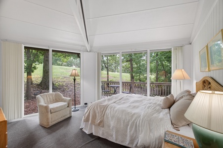 Wake to peaceful golf course views through floor-to-ceiling windows, where gentle light fills your serene bedroom retreat and invites you to unwind in comfort.