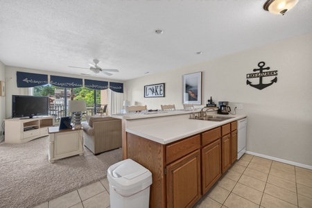 Relax in your open-concept living space where the kitchen flows seamlessly into the cozy living area, complete with lake-themed decor and a balcony overlooking the water.