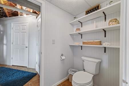 Your bright bathroom features crisp white walls, charming open shelving with coastal accents, and plenty of room to refresh after a day of exploring.