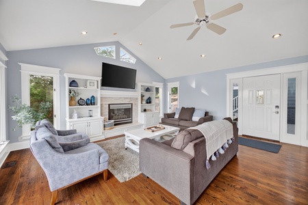 Relax in this bright, airy living room with vaulted ceilings and a cozy fireplace. Plush seating and sunlight streaming through multiple windows create your perfect retreat for unwinding after a day of exploring.