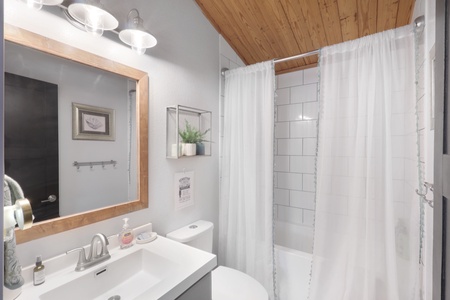 Freshen up in your stylish bathroom featuring crisp white subway tiles, warm wood accents, and thoughtful touches like fresh greenery. The well-lit vanity and spacious shower create your perfect retreat.