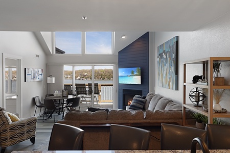 Unwind in your bright living space with soaring ceilings, cozy fireplace, and panoramic lake views through floor-to-ceiling windows.