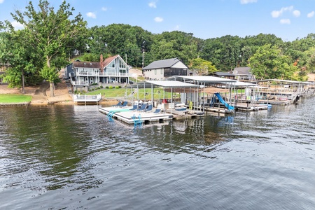Lakefront property featuring private dock access, boat slips, and a covered recreation platform. The property sits in a wooded lakeside community with mature trees and natural surroundings.