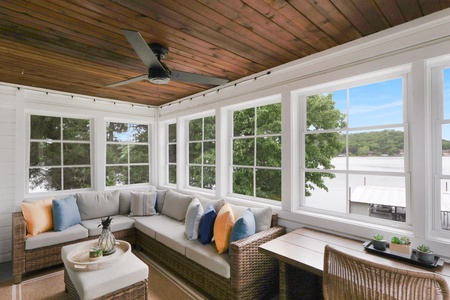 Sink into plush seating under the warm wood ceiling and gaze through floor-to-ceiling windows at peaceful lake views framed by lush greenery—your serene escape.