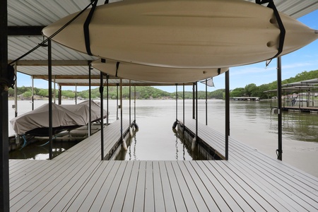 A private dock with covered boat slips provides your gateway to the lake, with wooded shores and peaceful waters waiting for your adventure.