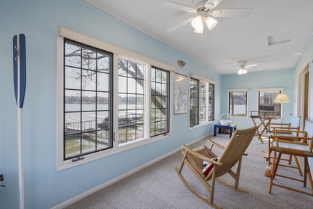 Settle into your peaceful lakefront sunroom where gentle breezes flow through open windows and lake views stretch endlessly before you.