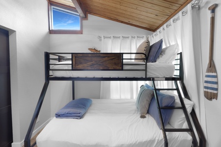 Your cozy bunk room features crisp linens and nautical touches beneath a warm wood-plank ceiling. Perfect for families or friends, the skylight brings in natural light and blue-sky views for a restful, airy feel.