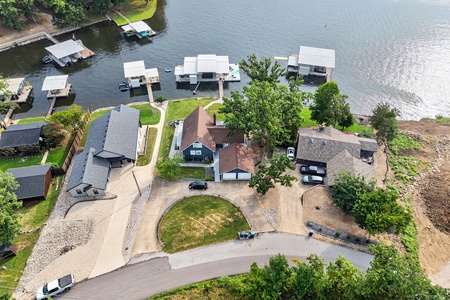 Aerial view of a tranquil waterfront property nestled along the lake, featuring private boat docks and access to peaceful waters surrounded by natural landscape and shaded trees.