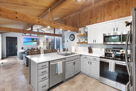 Step into your spacious, light-filled retreat with soaring wood-beamed ceilings and a fully equipped kitchen. Stainless steel appliances and a large island invite you to whip up meals while soaking in the open, airy ambiance.