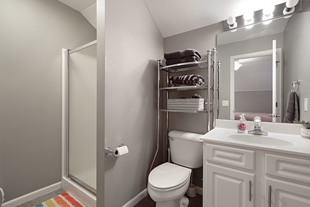 Your private bathroom features modern gray tones, a spacious shower, convenient storage, and fresh linens—perfect for refreshing after exploring.