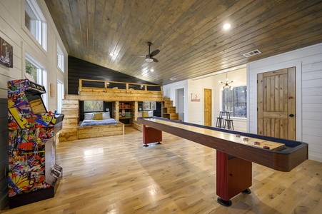 Upstairs bunk/game room features a shuffleboard table, arcade, and sleeping for 4-6 guests