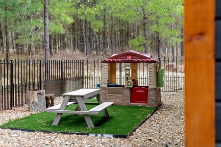 Dining table and toddler-size playset in a small fenced yard