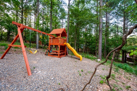 Outdoor playset with slide, swings, rock climbing wall, and treehouse