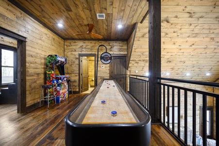 Upstairs game loft features a shuffleboard table, arcade, and card table