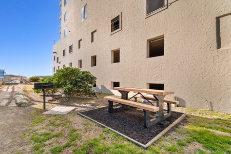 Property building exterior showcases modern design with outdoor seating area featuring picnic table for guest relaxation.